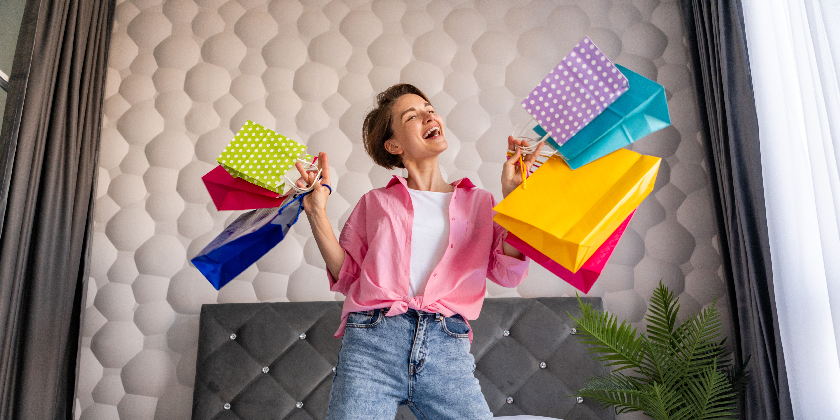 pretty happy woman having fun jumping bed home with colorful shopping bags